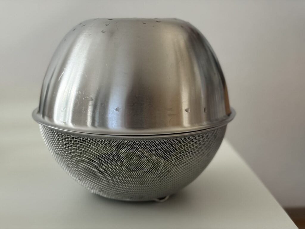 ボウルと丸ざるを向かい合わせにして振り、葉物野菜の水切りをしている写真